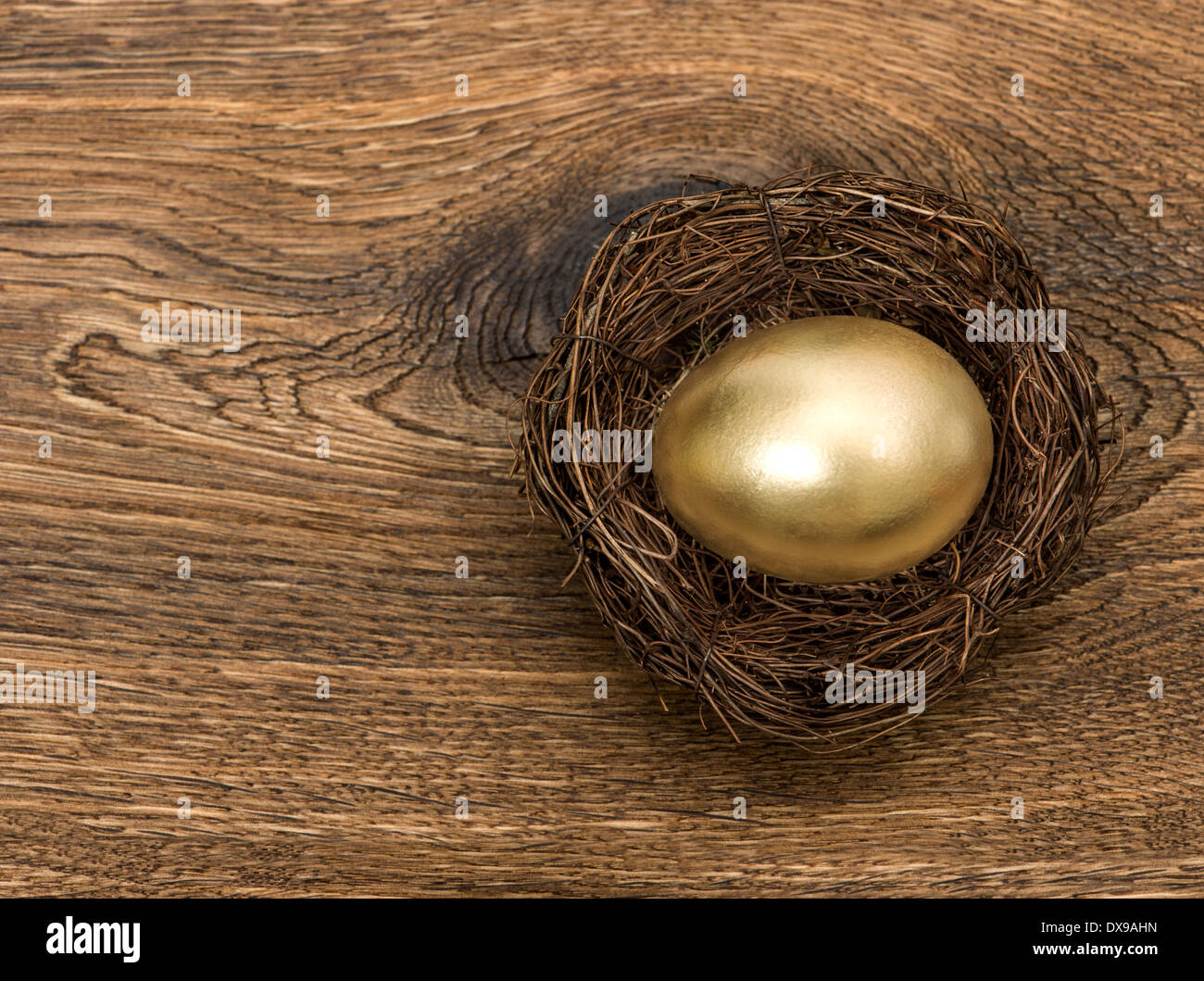 golden easter egg in nest over vintage wooden background Stock Photo