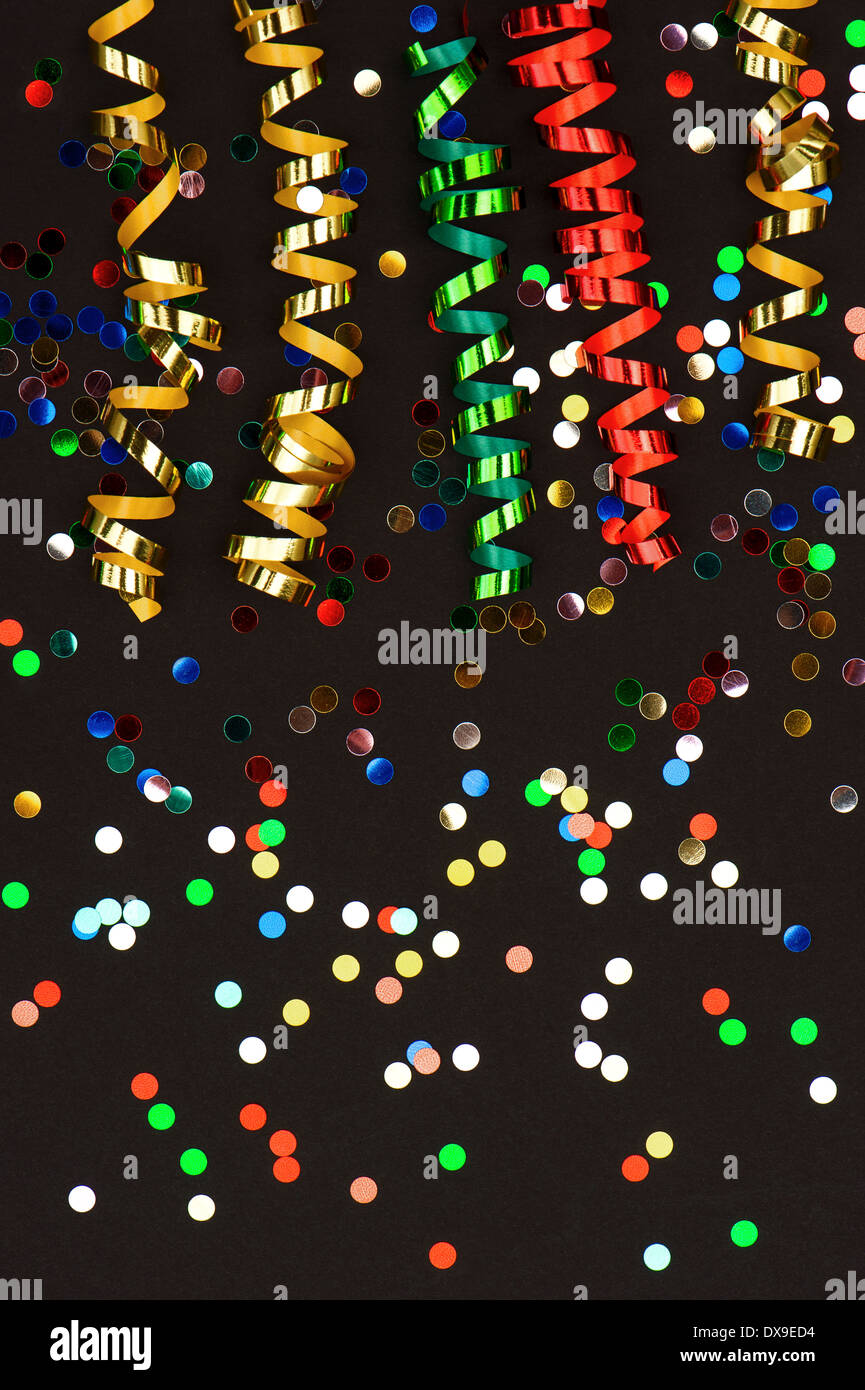 colorful streamer and confetti on black paper background. party decoration Stock Photo