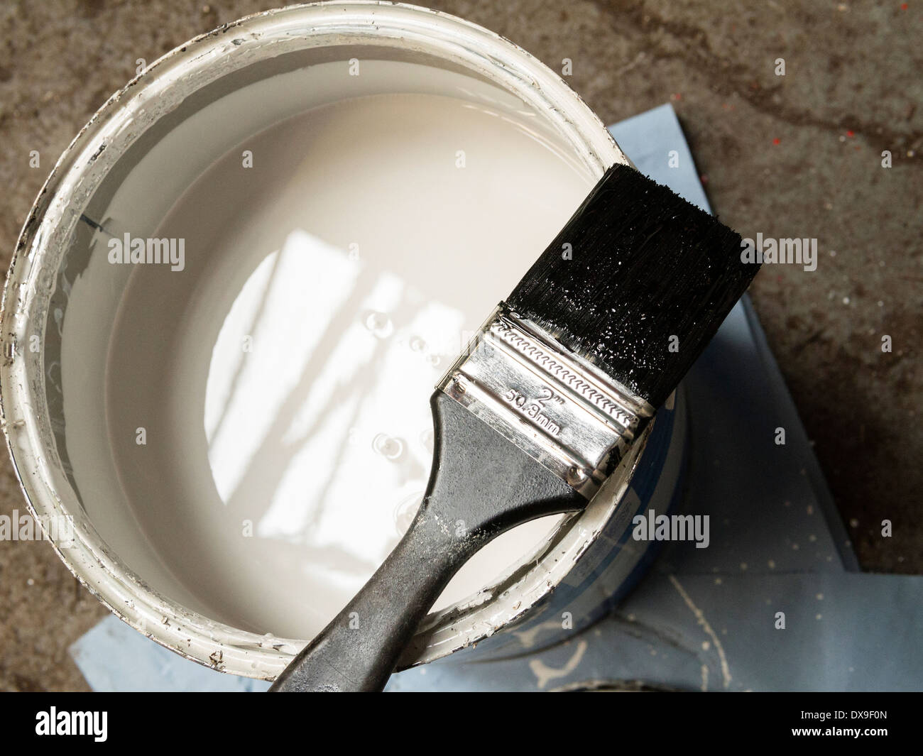 white paint tin with brush holding black paint Stock Photo