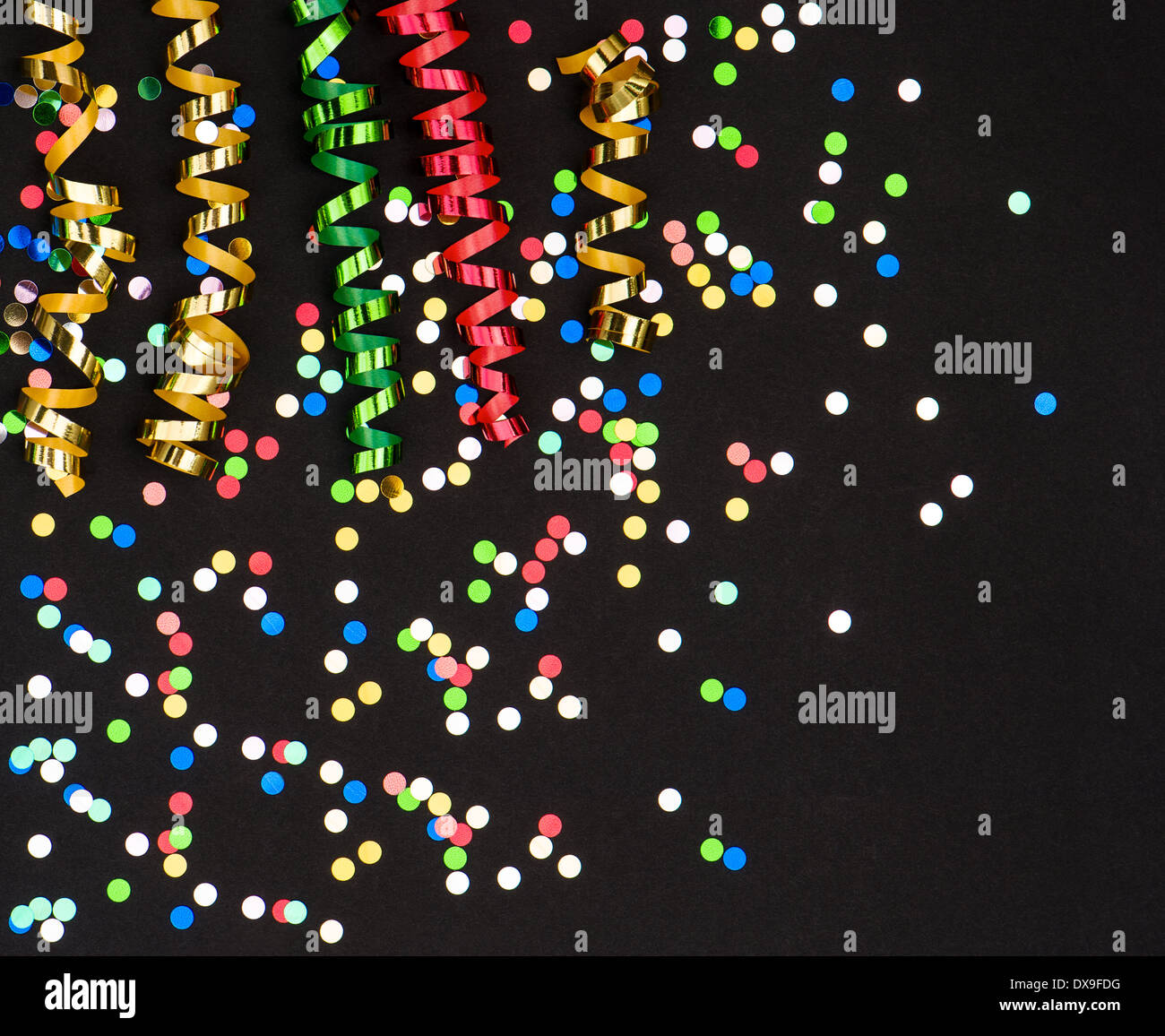 colorful streamer and confetti on black paper background. party decoration Stock Photo