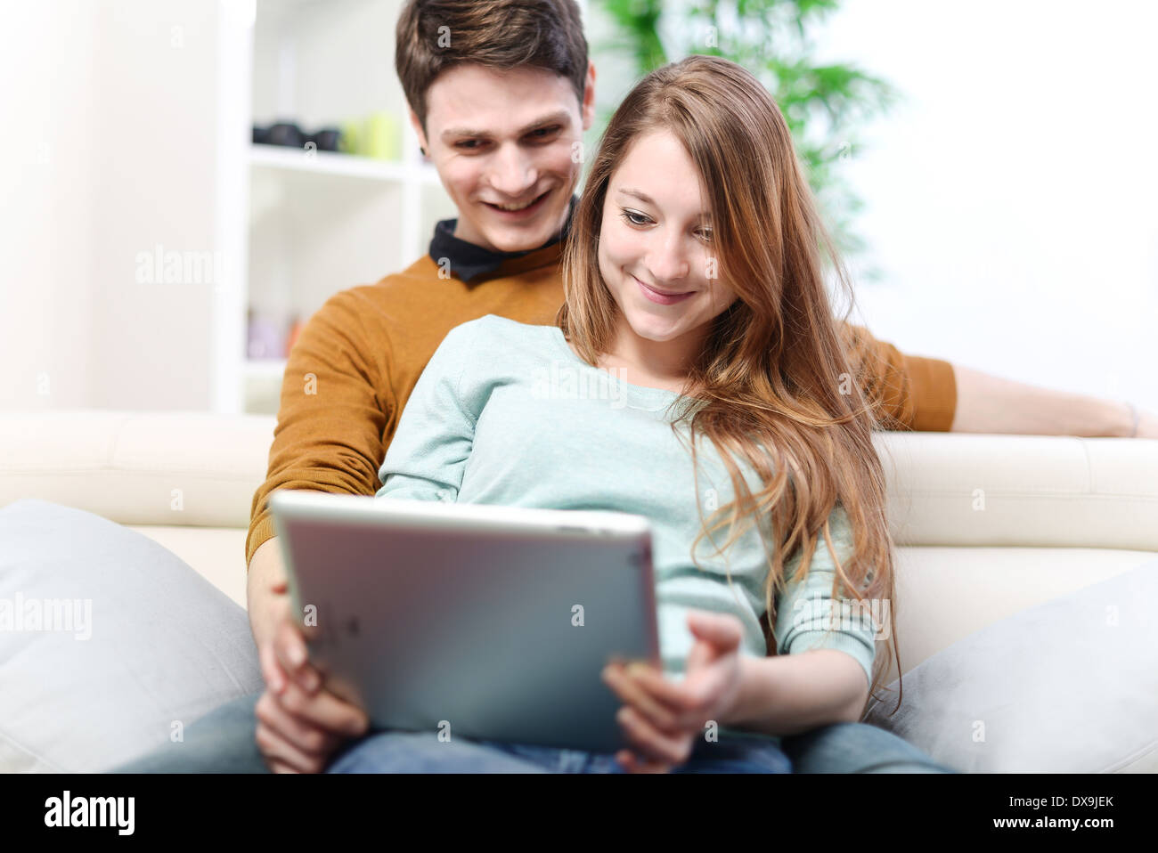 Young couple using digital tablet indoors on the sofa Stock Photo