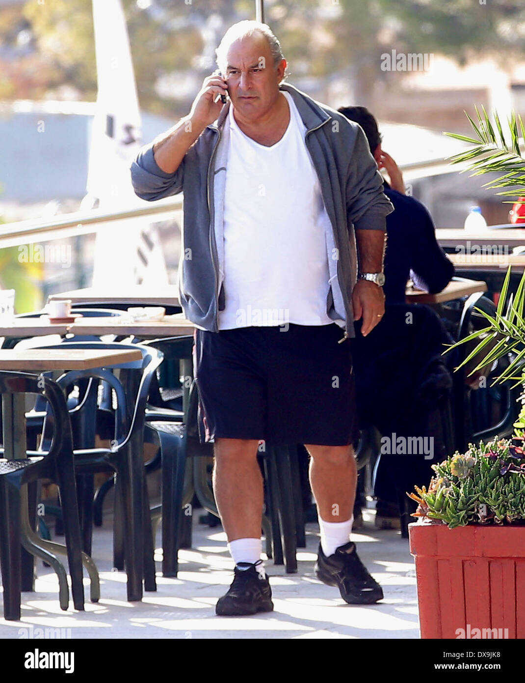 Sir Philip Green chatting on his mobile phone while walking by the