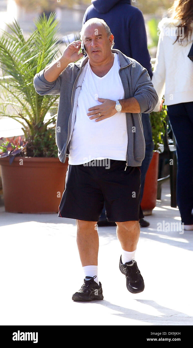 Sir Philip Green chatting on his mobile phone while walking by the