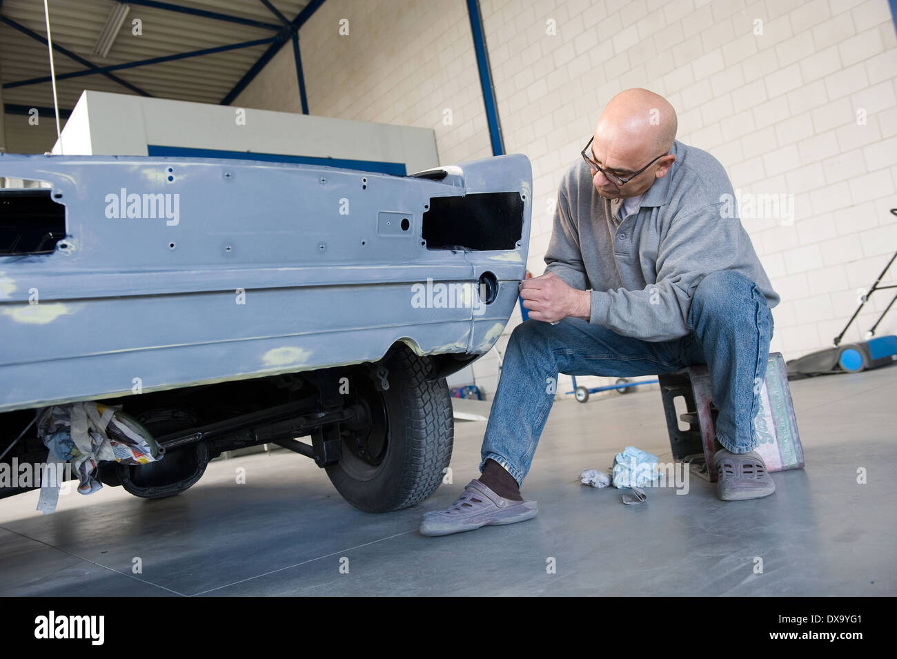 A car repairman is restoring the carbody of an old timer for repainting in a garage Stock Photo