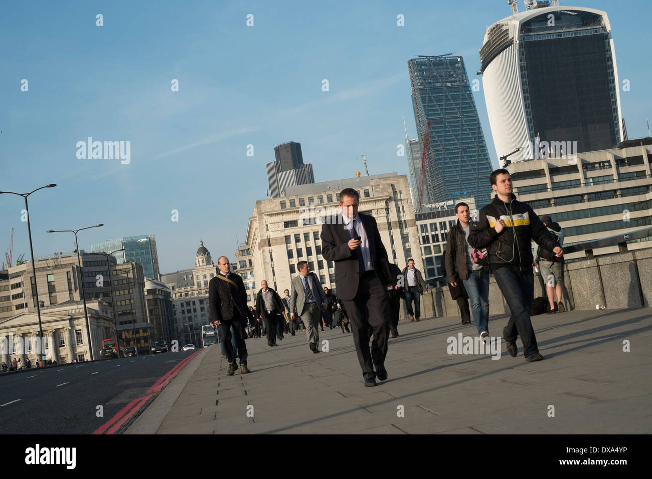 Commuters walking across London Bridge on their mobile phones Stock