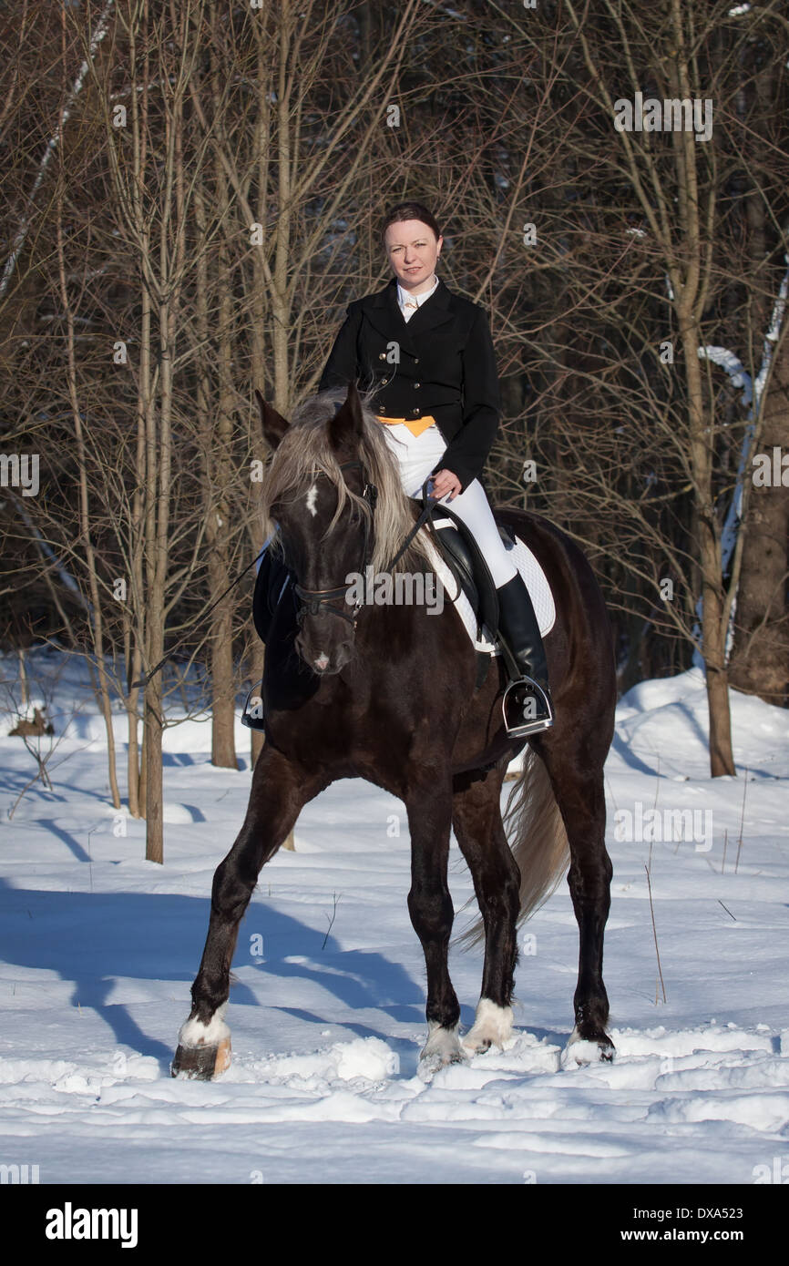 Young woman riding a horse through woodland Stock Photo