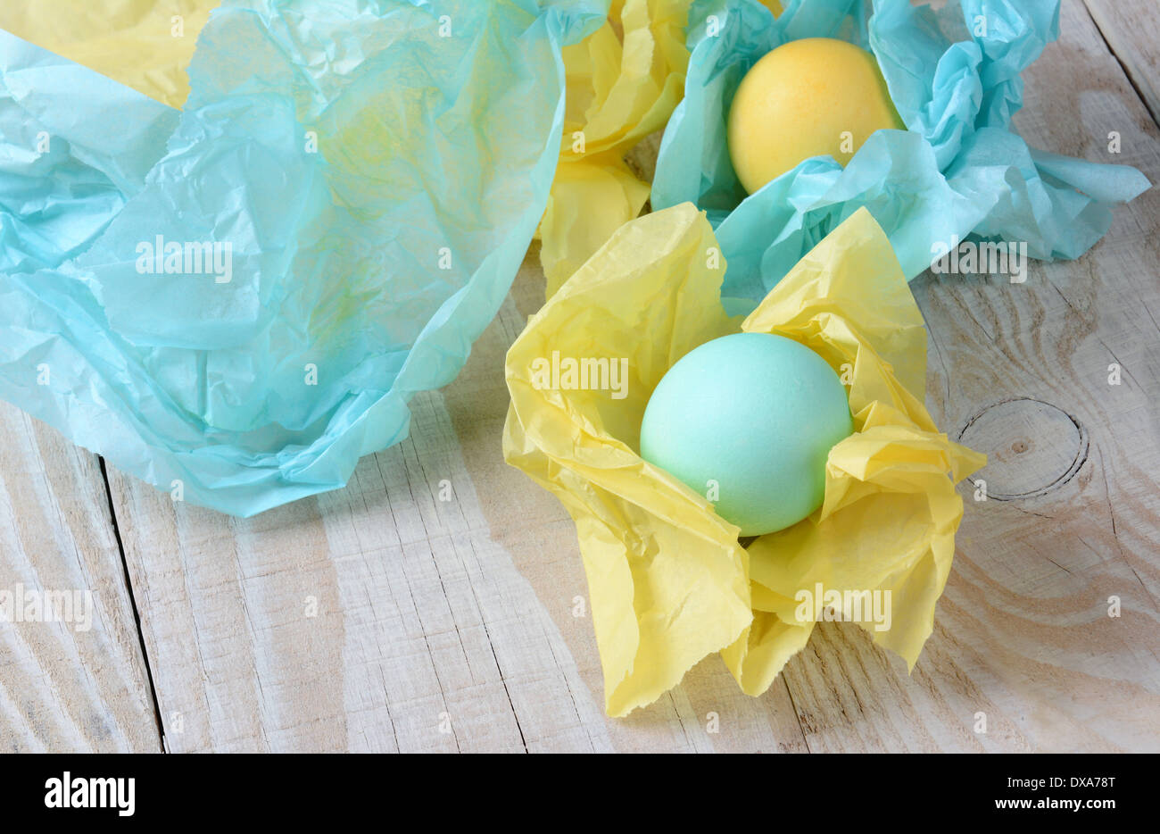 High angle view of pastel Easter eggs wrapped with tissue paper. Shallow depth of field with focus on the front egg. Stock Photo
