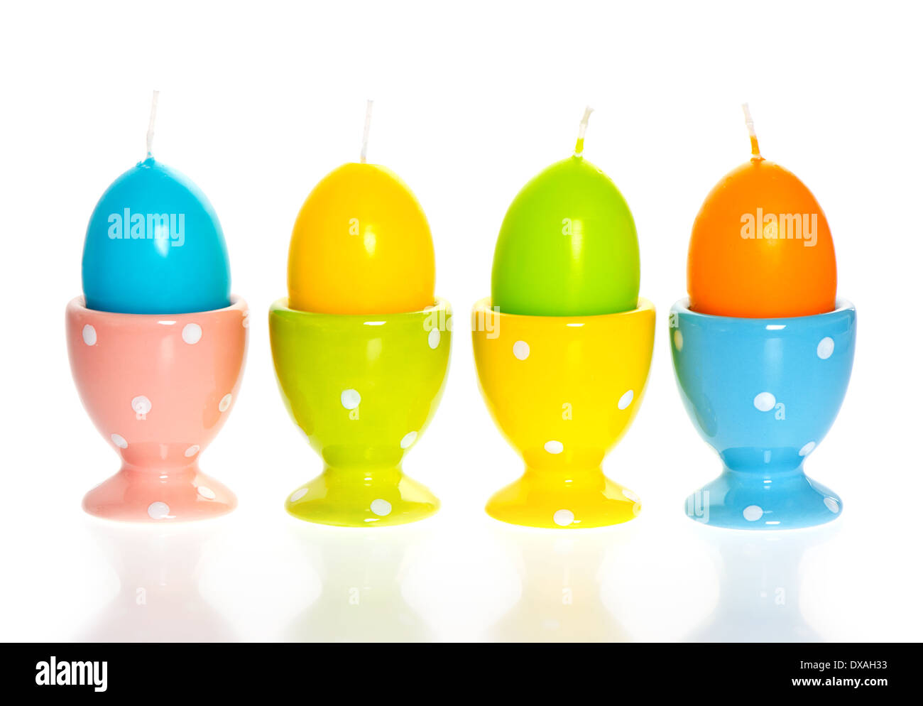 multicolored easter eggs candles in eggcups on white background Stock Photo