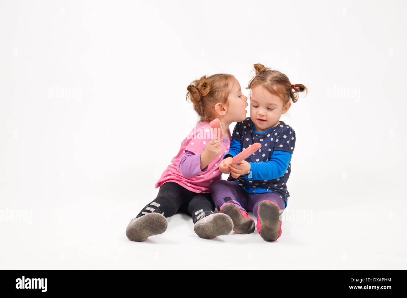 Twin girls eating ice cream and kissing Stock Photo