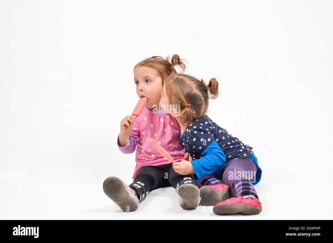 Twin girls eating ice cream and kissing Stock Photo