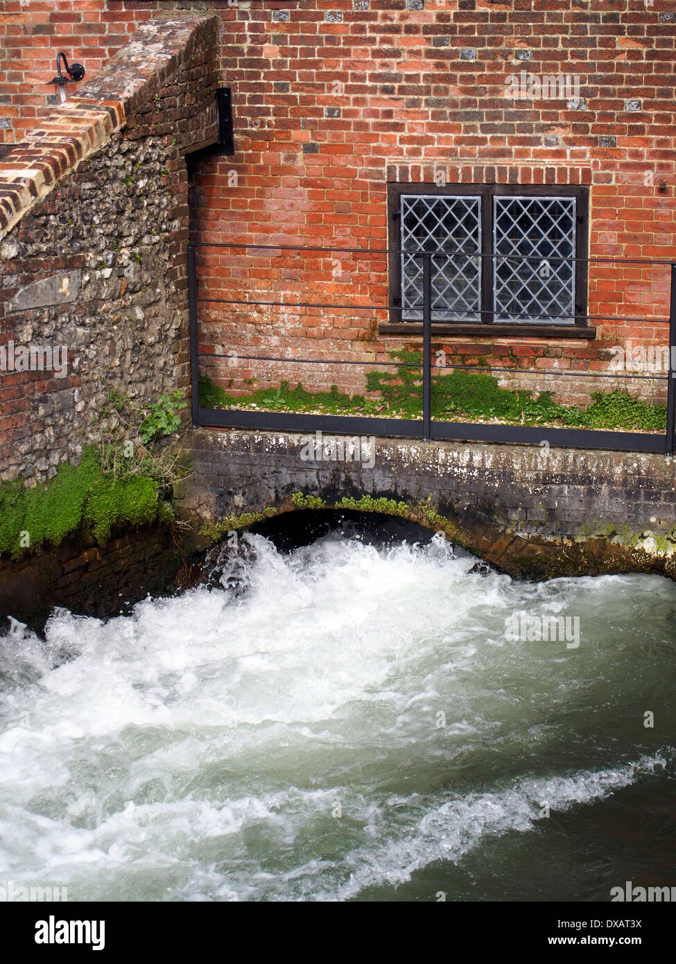A torrent of water flows from the wheel pit of Winchester City Mill, a watermill in the heart of this historic city. Stock Photo