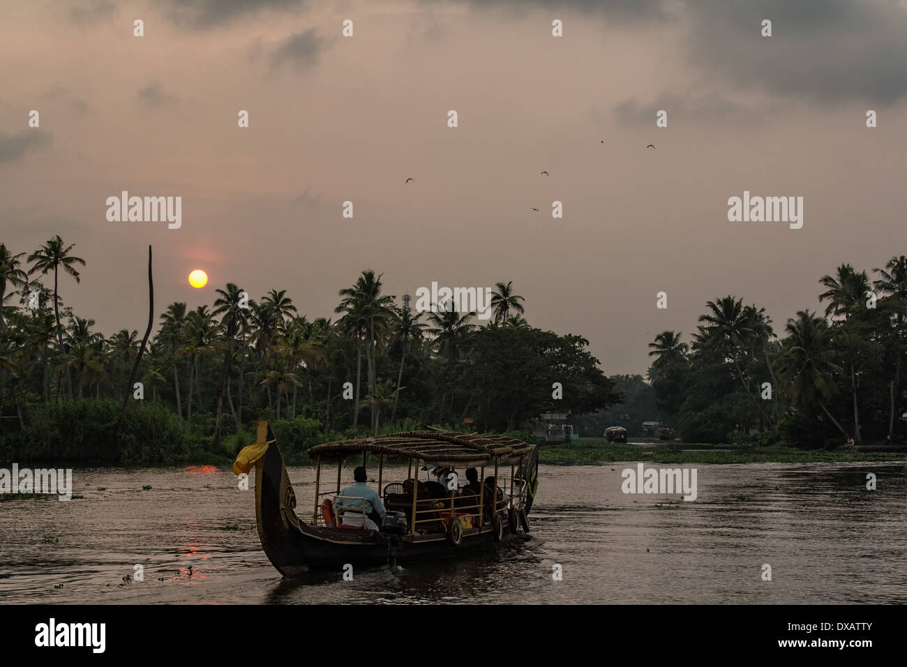 Riverboat carrying passengers on the river in the Alleppey Backwaters at sunset in Kerala, India Stock Photo