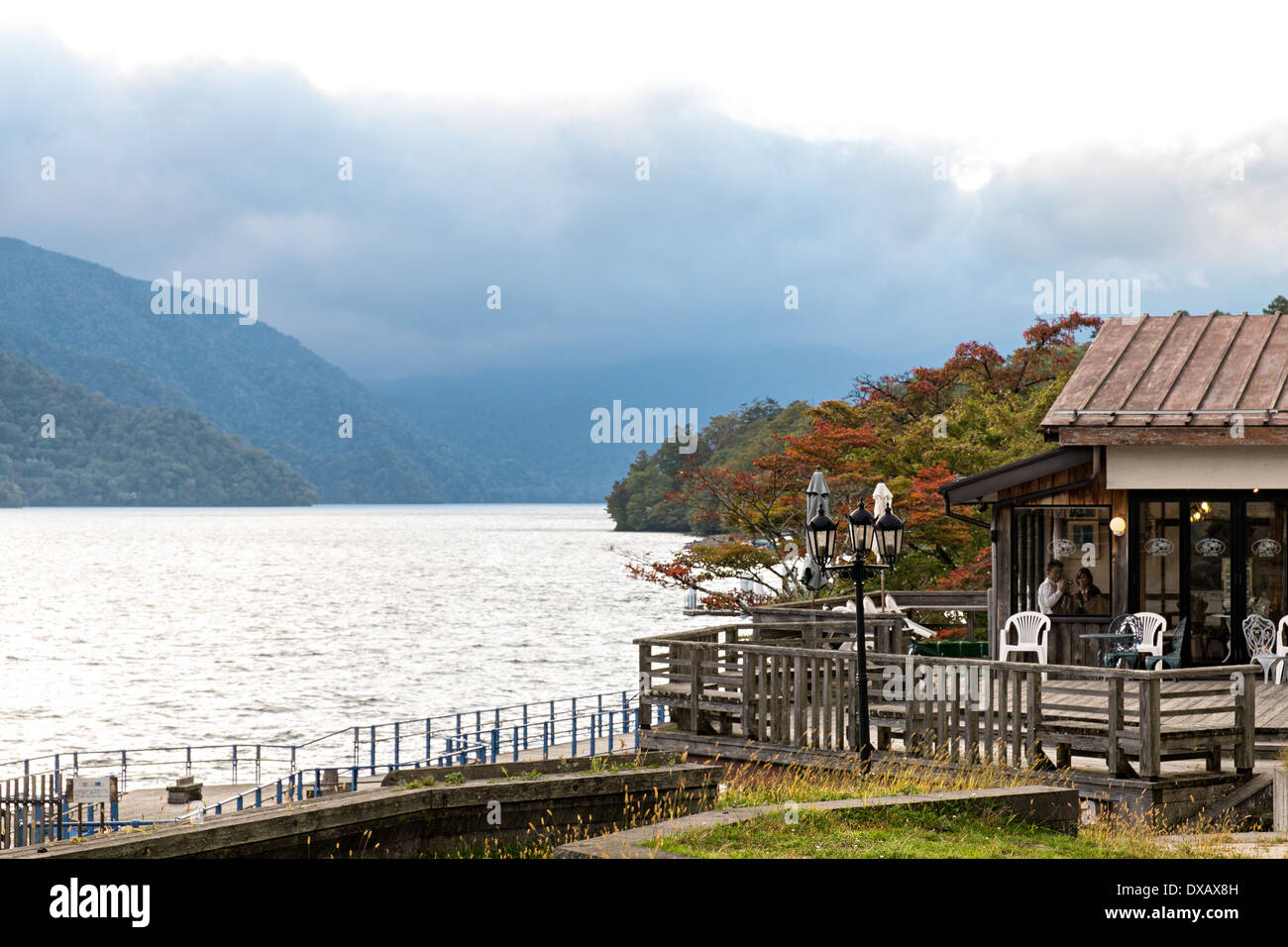 Teahouse on pier at Lake Chuzenji with mountains and fog iat the hot spring town of Chuzenjiko Onsen in Nikko, Japan Stock Photo