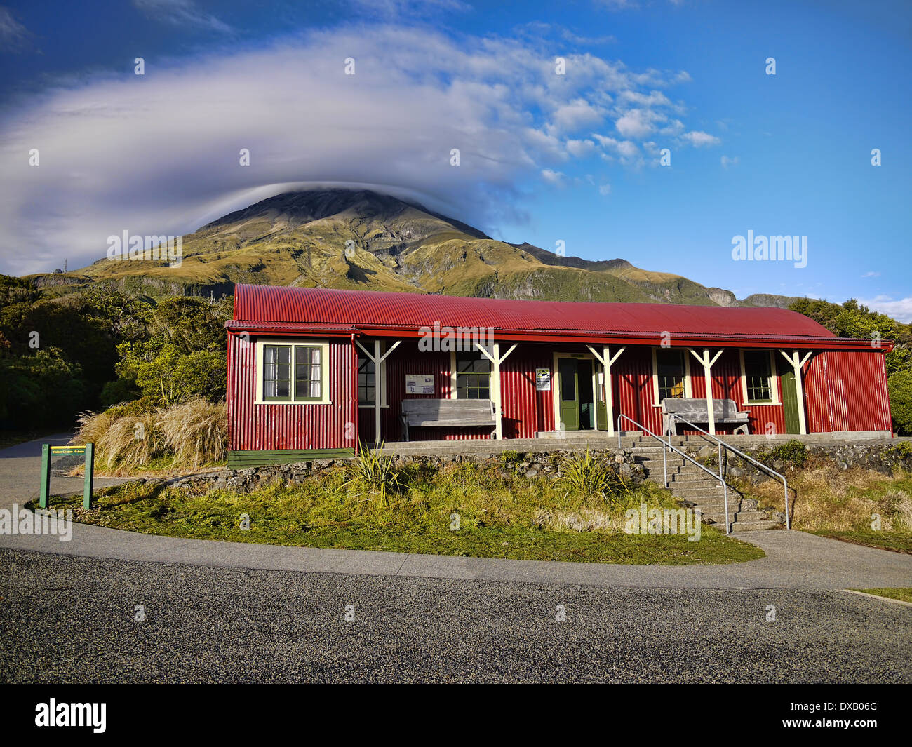 View of the volcano Mount Taranaki (Mt Egmont) Egmont National Park and the red camphouse corrugated iron building Stock Photo