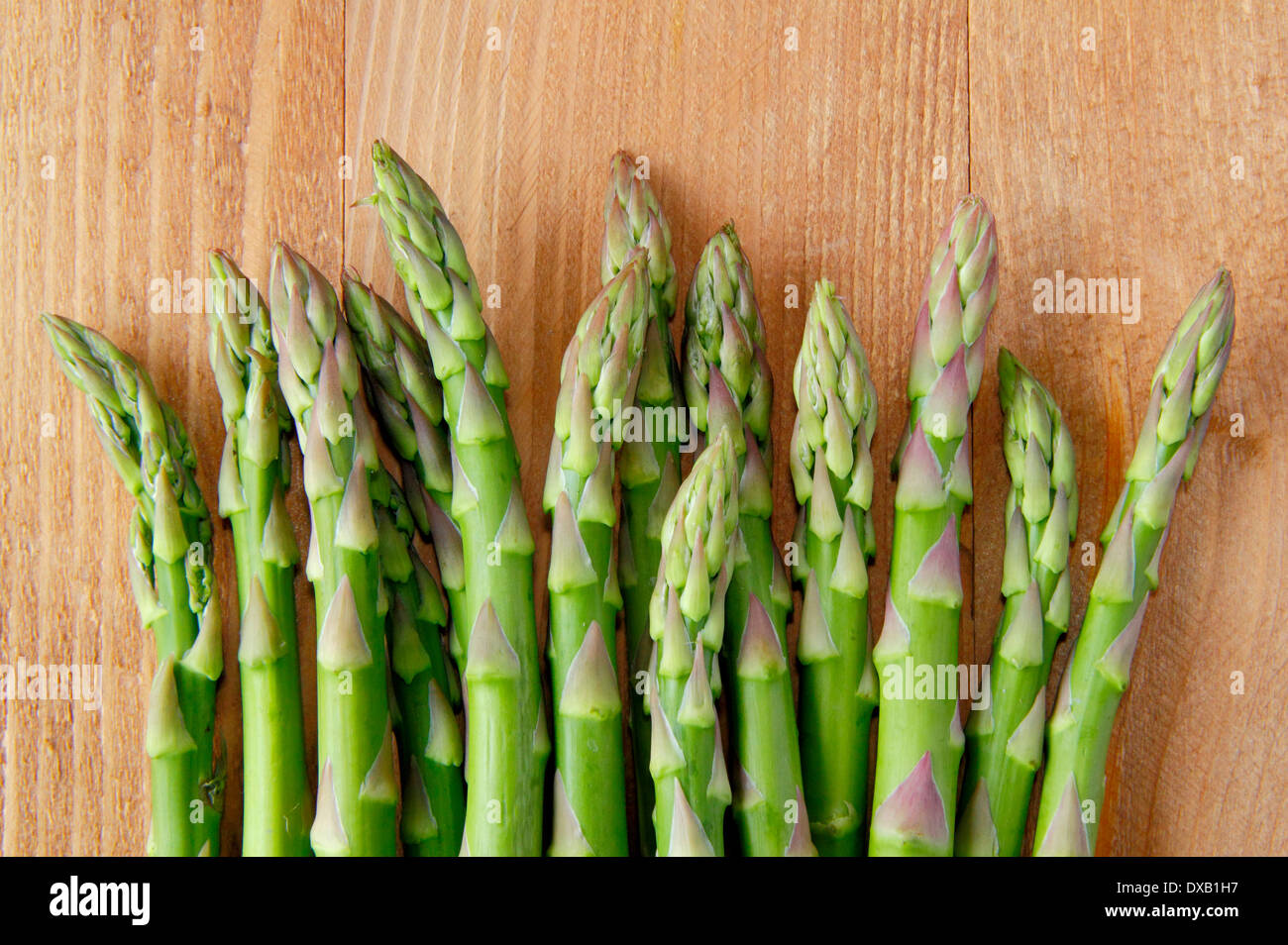 Fresh green asparagus tips/stalks against wooden background, UK Stock Photo
