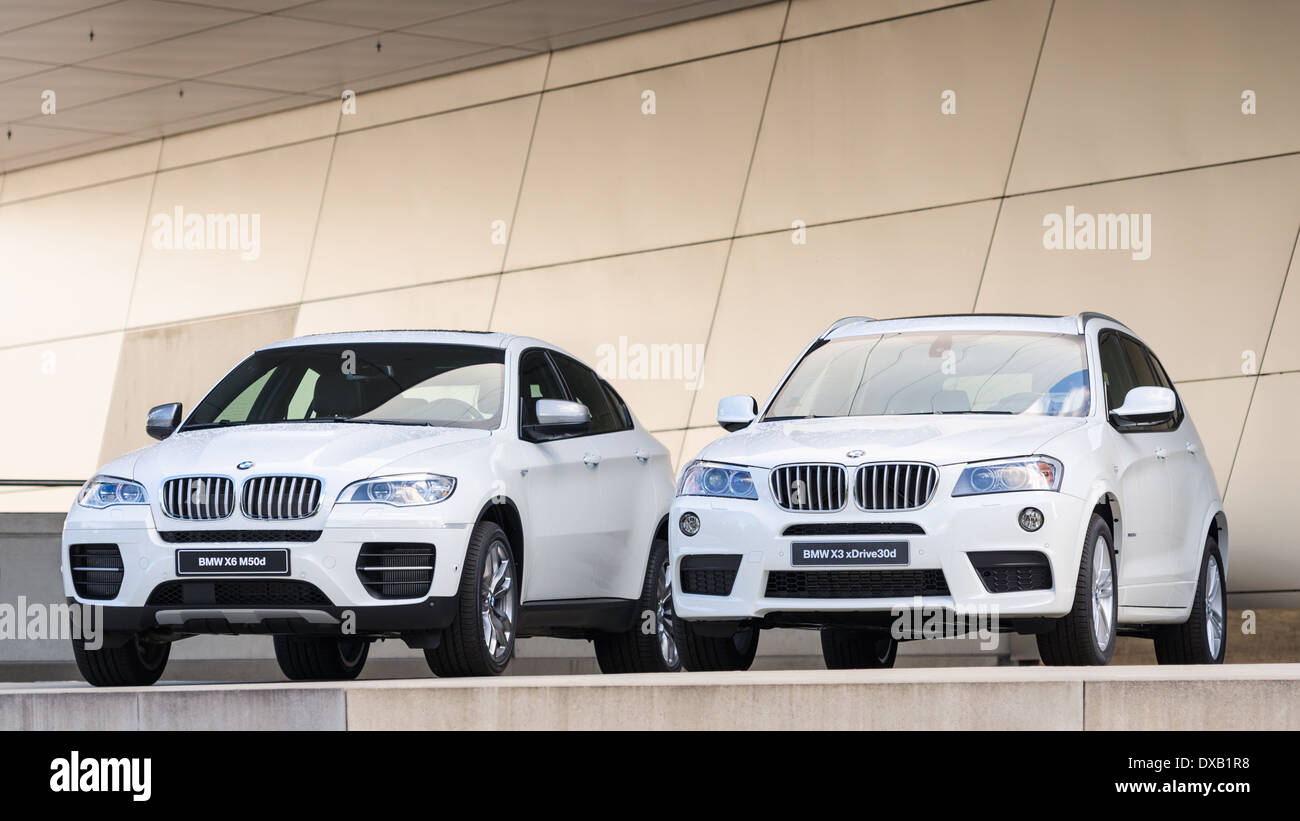 New models of X3 X6 SUV presented in BMW Welt show. Two white cars on podium wet after rain. Stock Photo