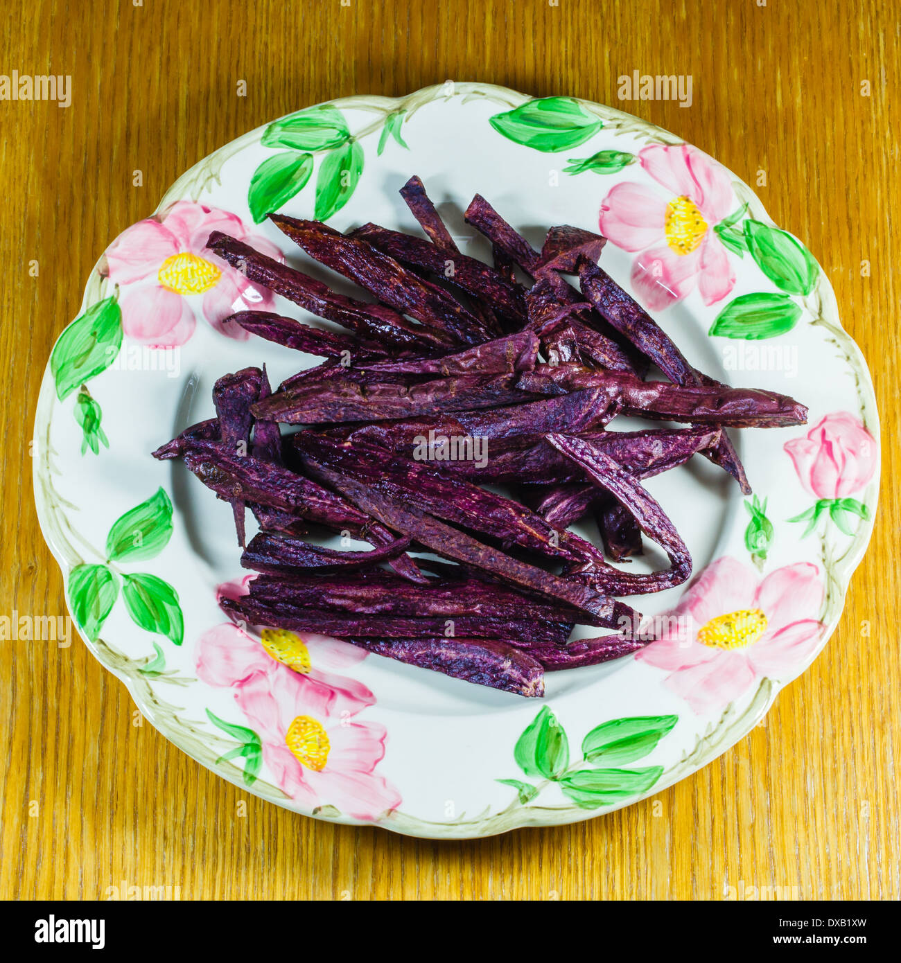 A decorative plate with a heap of purple sweet potato fries ready to be eaten Stock Photo