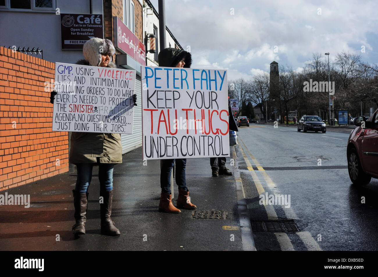 Swinton, Salford, Manchester, UK . 22nd March 2014. Anti-fracking campaigners protest outside Swinton police station, Salford, Manchester. Two ladies standing opposite the police staion displaying protest signs from passing motorists to see. Both signs infer that the Greater Manchester Police behave violently. Credit:  Dave Ellison/Alamy Live News Stock Photo
