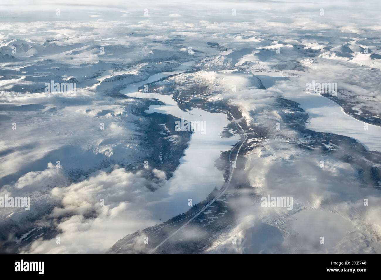 Majestic aerial view of frozen Northern Sweden. High mountain ranges and frozen rivers and lakes with low clouds. Stock Photo
