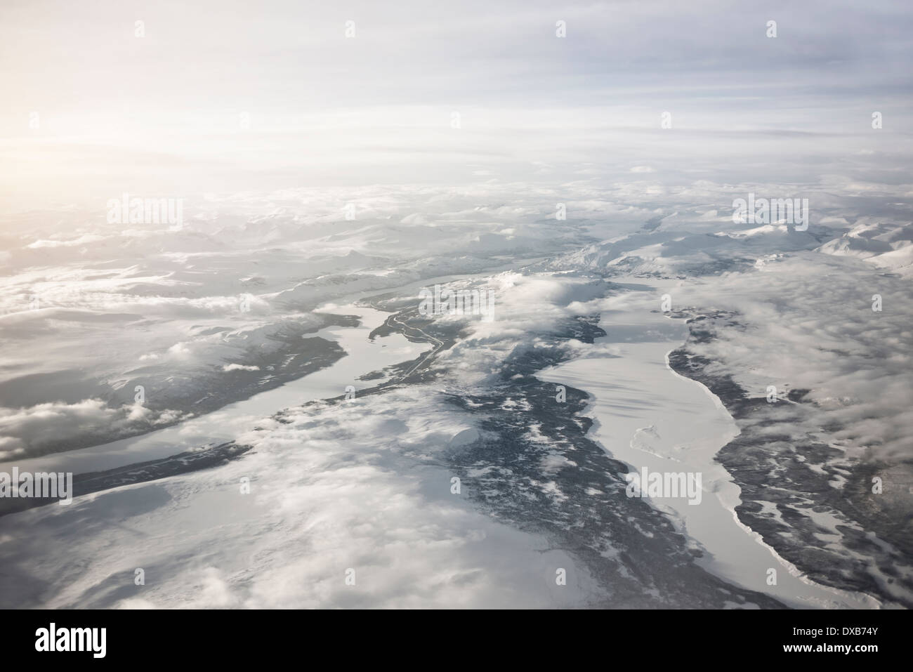 Majestic aerial view of frozen Northern Sweden. High mountain ranges and frozen rivers and lakes with low clouds. Stock Photo