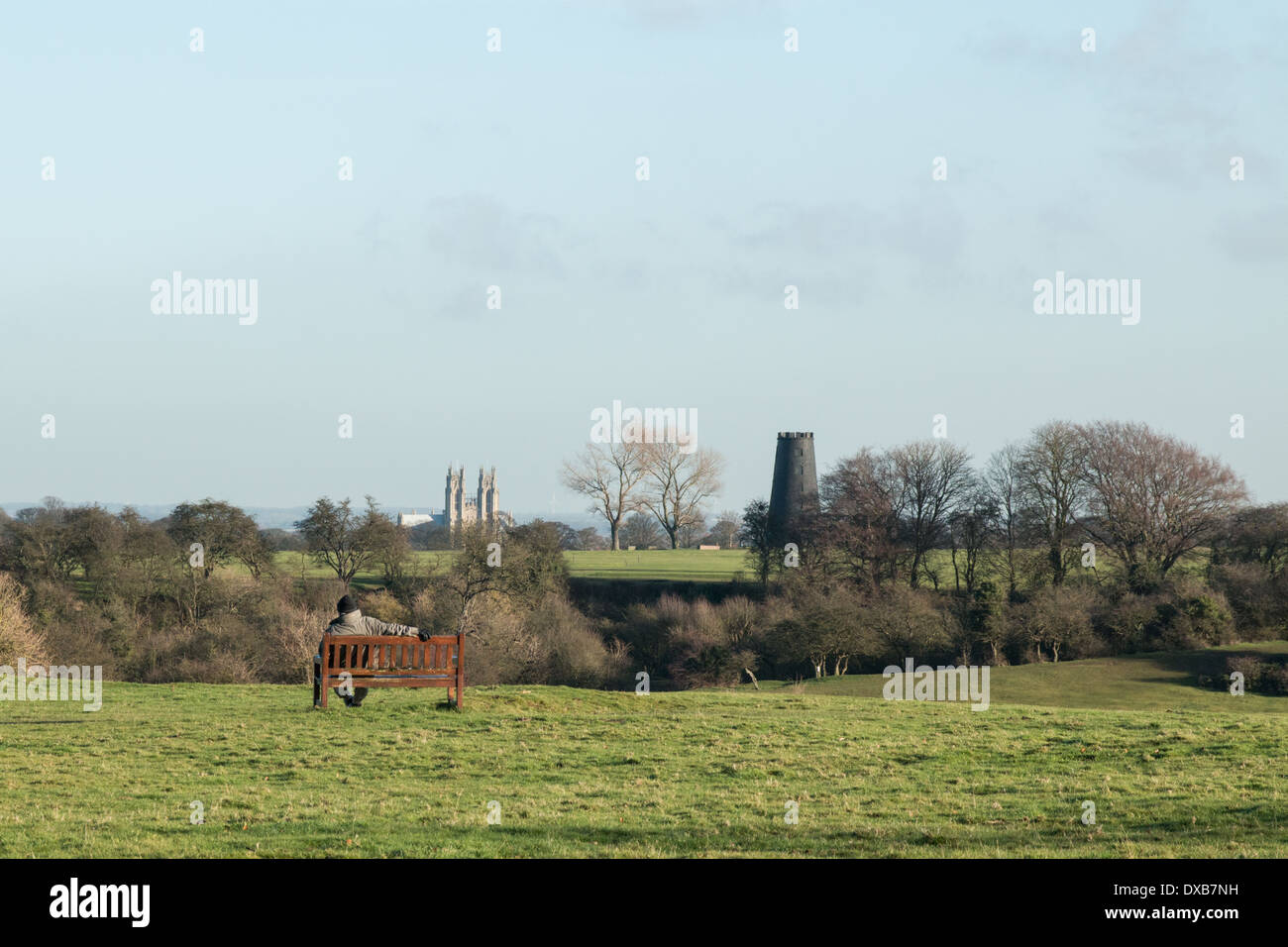 Man sitting on a seat looking towards Beverley town on Beverley Westwood, East Yorkshire UK Stock Photo
