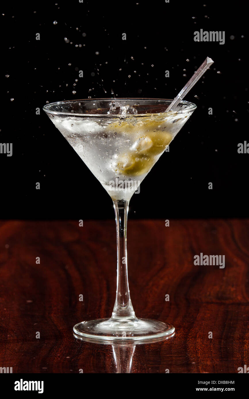 close up of garlic stuffed martini olives splashing into a cocktail