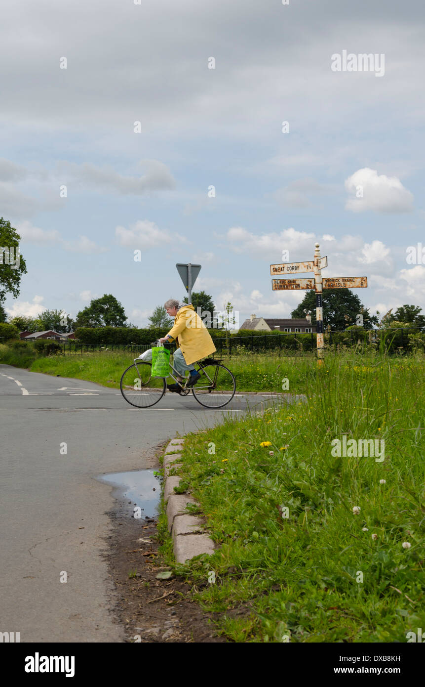 An old fashioned cyclist (no Lycra!) at a road crossing North of Carlisle, England Stock Photo