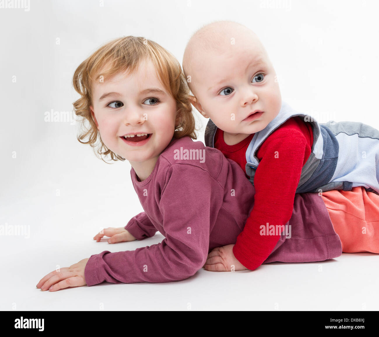 two siblings playing on floor. studio shot in grey background Stock Photo