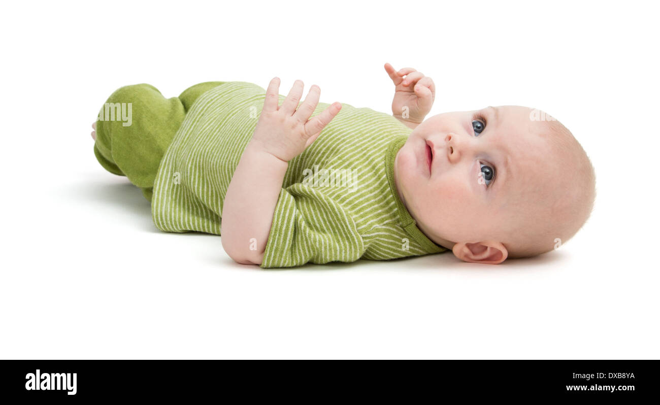 toddler in green clothing laying on back in white background Stock Photo