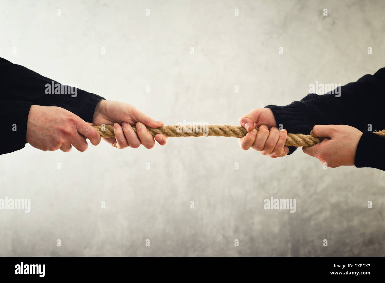 Tug of war. Female hands pulling rope to opposite sides. Rivalry concept. Stock Photo