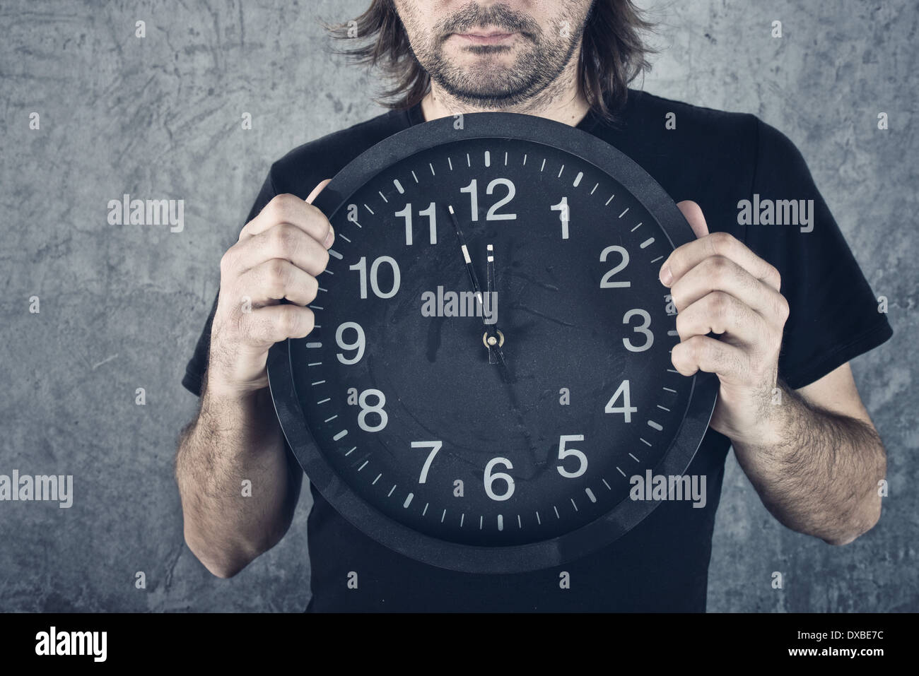 Man holding big black clock, two minutes to midnight Stock Photo - Alamy