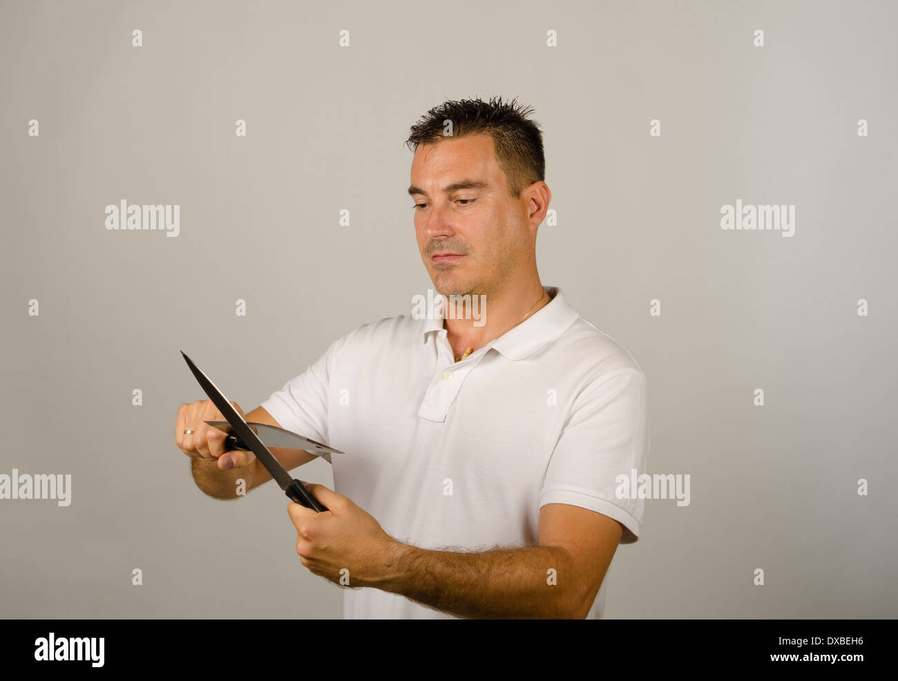 Man whetting a kitchen knife and an axe Stock Photo - Alamy