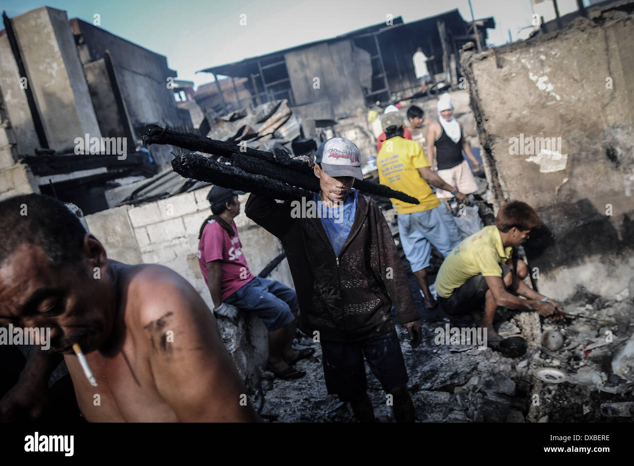 Caloocan, Philippines. 23rd Mar, 2014. A resident collects scrap wood from the rubble of burnt shanties after a fire gutted a residential area in Caloocan city, north of Manila, Philippines, March 23, 2014. At least 1700 families have been left homeless after 3 separate fires gutted 700 homes in a span of 24 hours. The fires took place as the country observes Fire Prevention Month.Photo: Ezra Acayan/NurPhoto Credit:  Ezra Acayan/NurPhoto/ZUMAPRESS.com/Alamy Live News Stock Photo