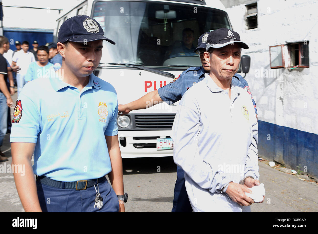 Quezon City, Philippines. 23rd Mar, 2014. Benito Tiamzon (R), chairman of the Communist Party of the Philippines (CPP)-NPA, is handcuffed as he walks with policemen at Camp Crame in Quezon City, the Philippines, March 23, 2014. The Philippine government expressed readiness on Sunday to protect the citizenry against any retaliatory attacks that the leftist New People's Army (NPA) would launch following the arrest of its two top leaders. Credit:  PNP HANDOUT PHOTO/Xinhua/Alamy Live News Stock Photo