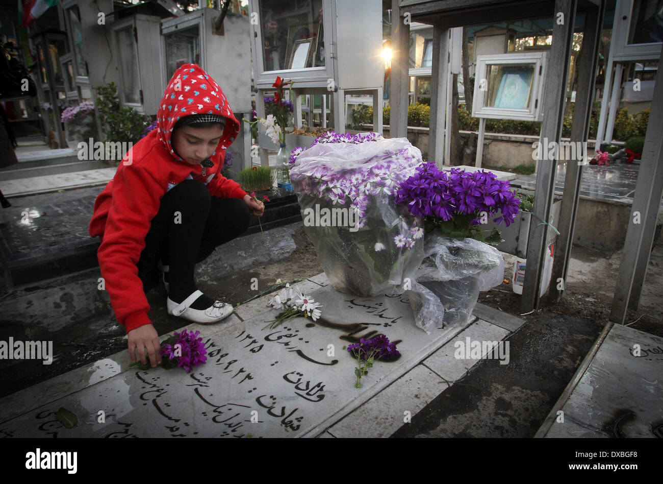 Tehran, Iran. 22nd Mar, 2014. An Iranian girl puts flowers at the cemetery of soldiers who were killed during the 1980-88 Iran-Iraq war, in Tehran, Iran, March 22, 2014. Credit:  Ahmad Halabisaz/Xinhua/Alamy Live News Stock Photo