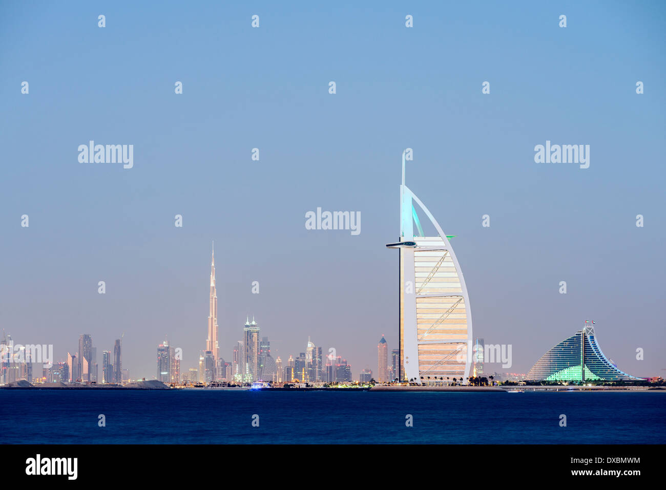 Night skyline across sea to luxury Burj al Arab hotel and city of Dubai with Burj Khalifa tower in distance in United Arab Emira Stock Photo
