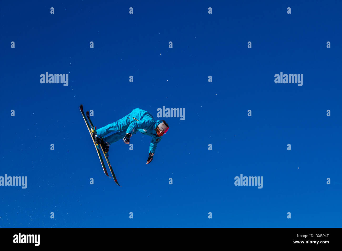 Ski instructor practising and demonstrating ski jumping, landing on a