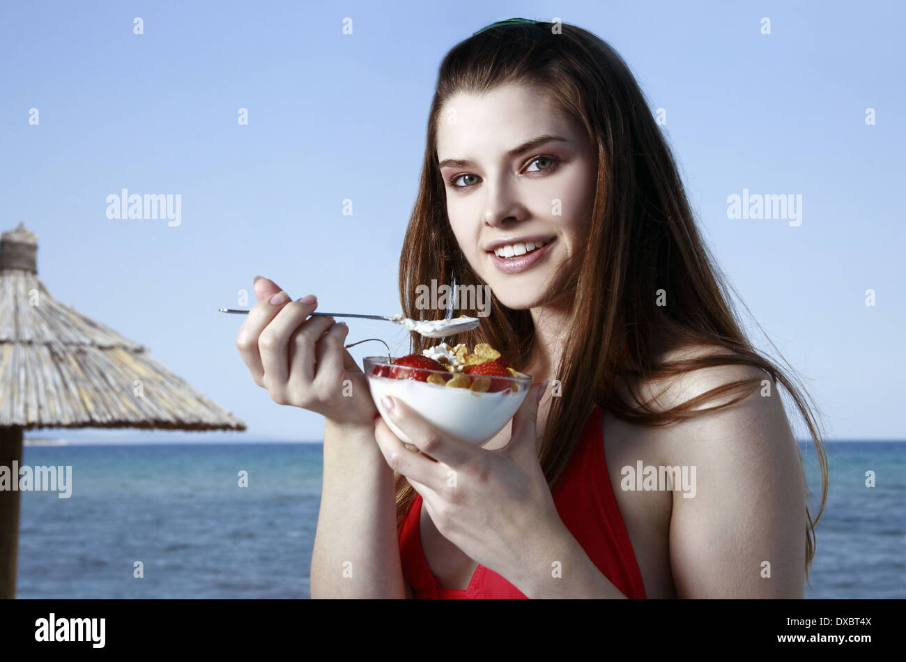 Female young adult eating fruit and yogurt on beach Stock Photo Alamy