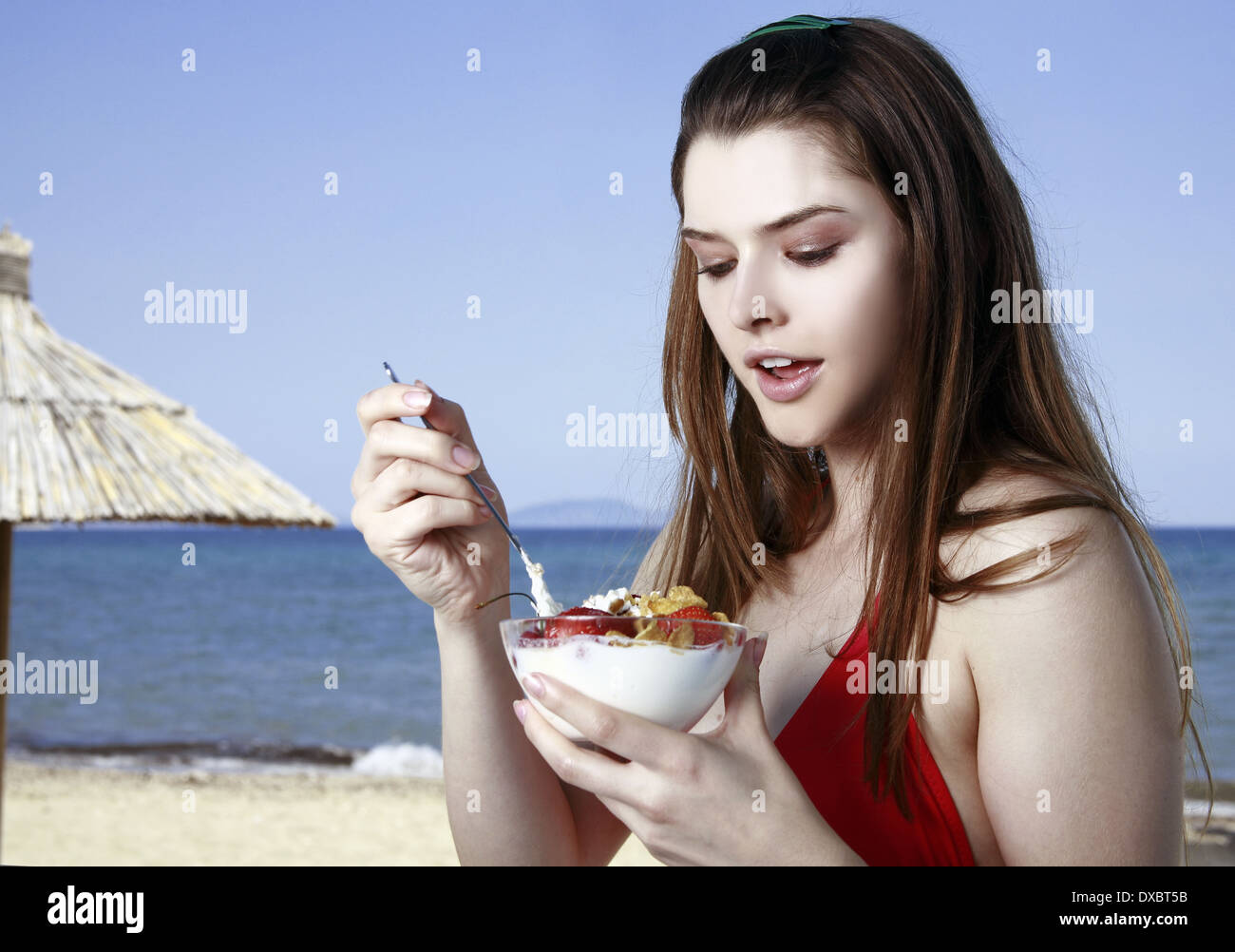 Female young adult eating fruit and yogurt on beach Stock Photo Alamy