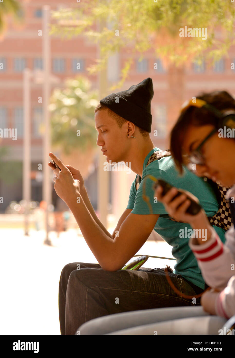 A young man texts on a college campus. Stock Photo