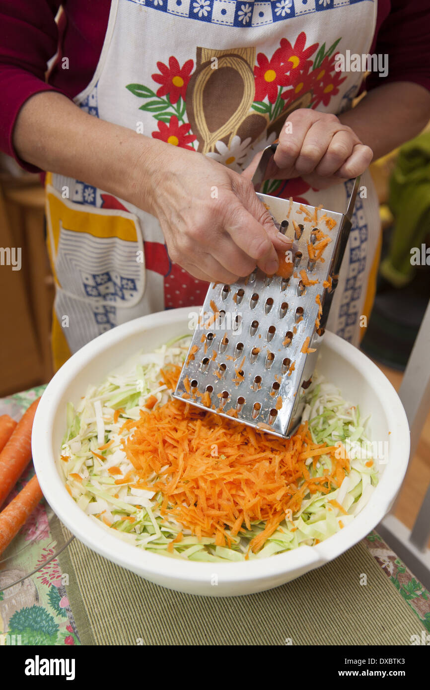 Woman makes cabbage salad, (sauerkraut) Polish style. Stock Photo