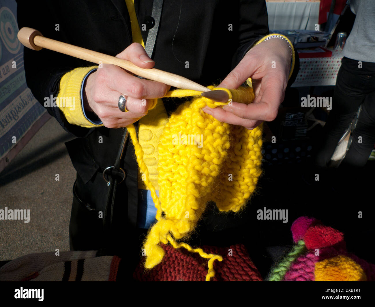 Woman with chunky yellow wool hat with big wooden knitting needles at  Spitalfields Market stall London UK KATHY DEWITT Stock Photo - Alamy