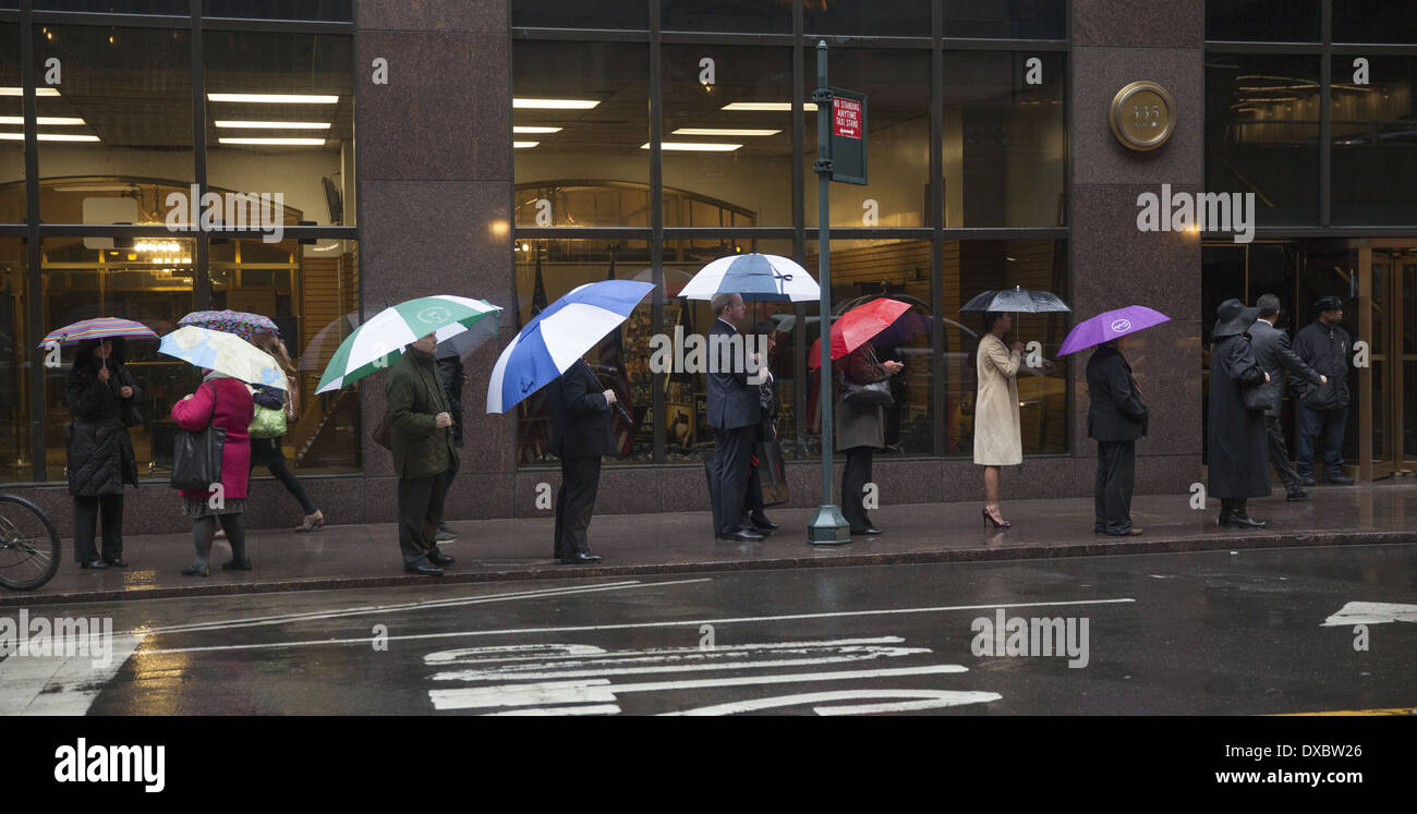 People wait for a public bus outside Grand Central Station on a rainy afternoon in NYC. Stock Photo