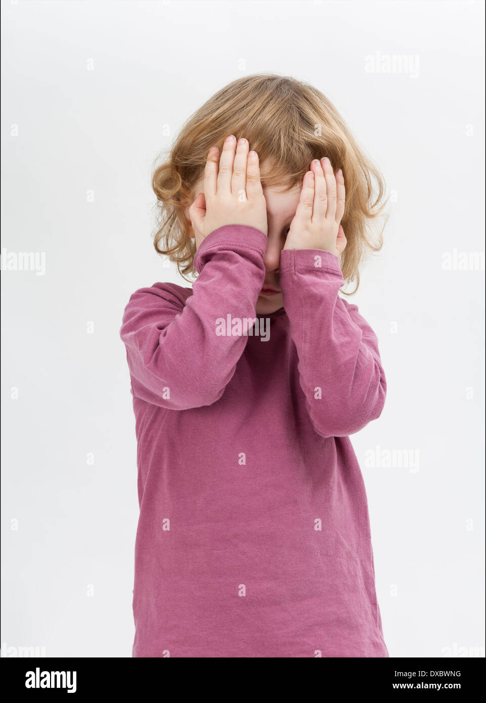 child covering eyes with hands. studio shot in grey background Stock Photo