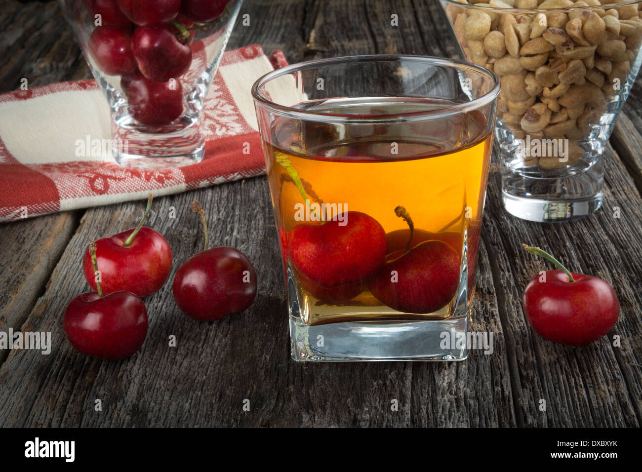 Manhattan or other whiskey cocktail, with cherries submerged and cherries and peanuts next to it Stock Photo