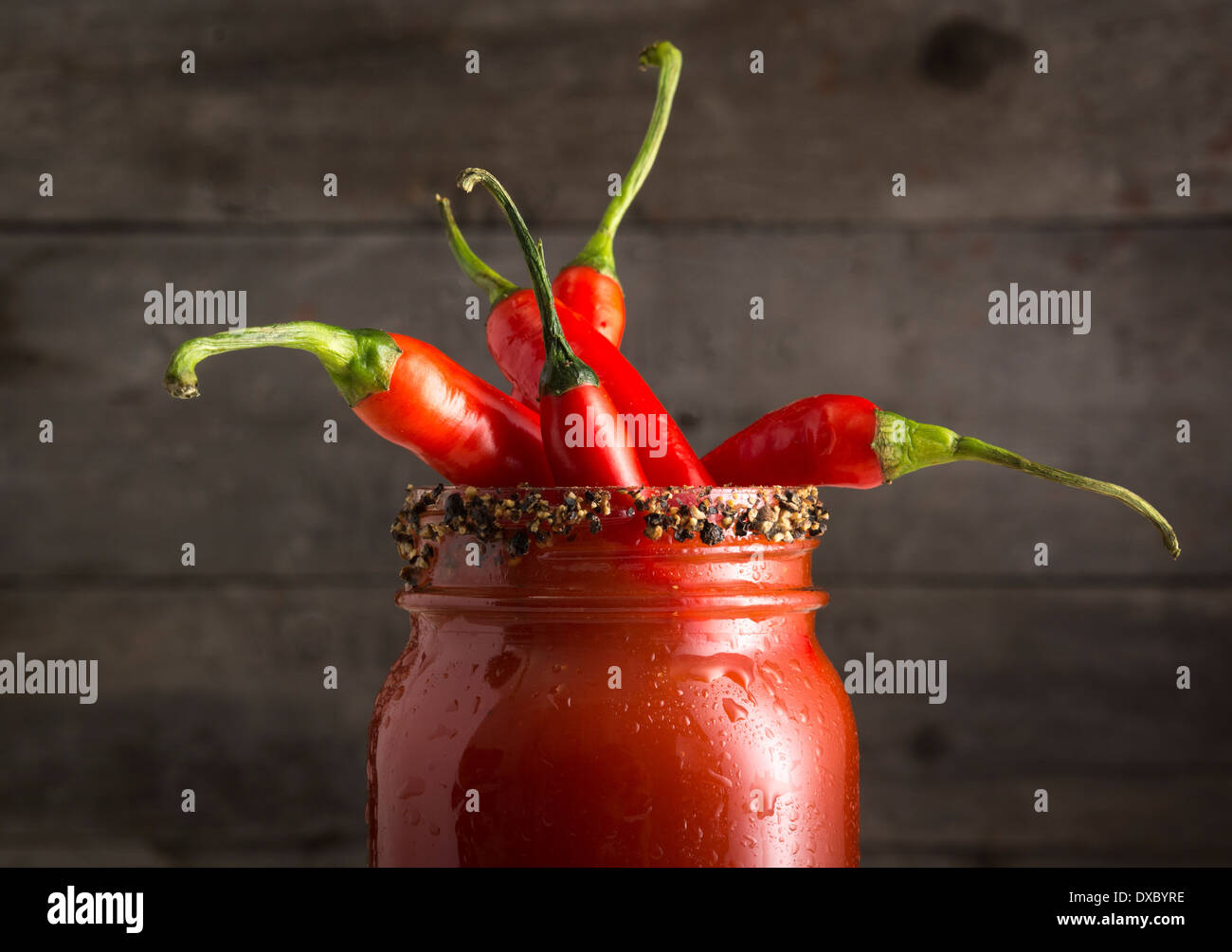 Closeup of Bloody Mary or Bloody Ceasar cocktail in mason jar rimmed with black pepper and filled with red jalapeno peppers Stock Photo