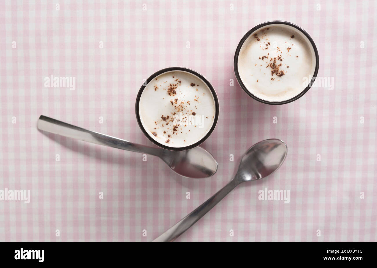 Cappuccino in pink cup with cocoa and almond milk foam and spoons Stock Photo