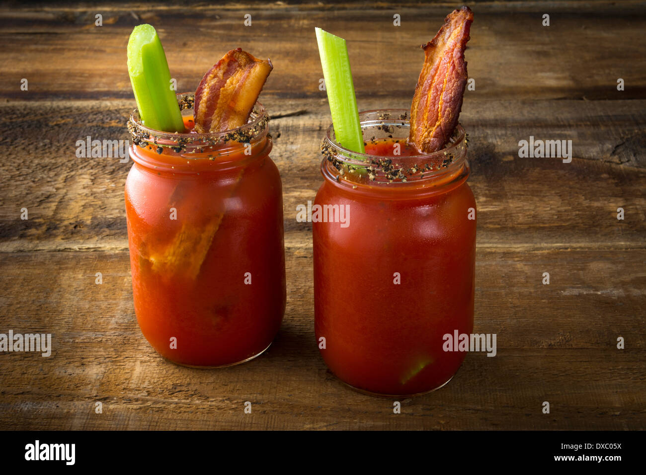 Two mason jar Bloody Marys or Caesars with bacon on wood background Stock Photo
