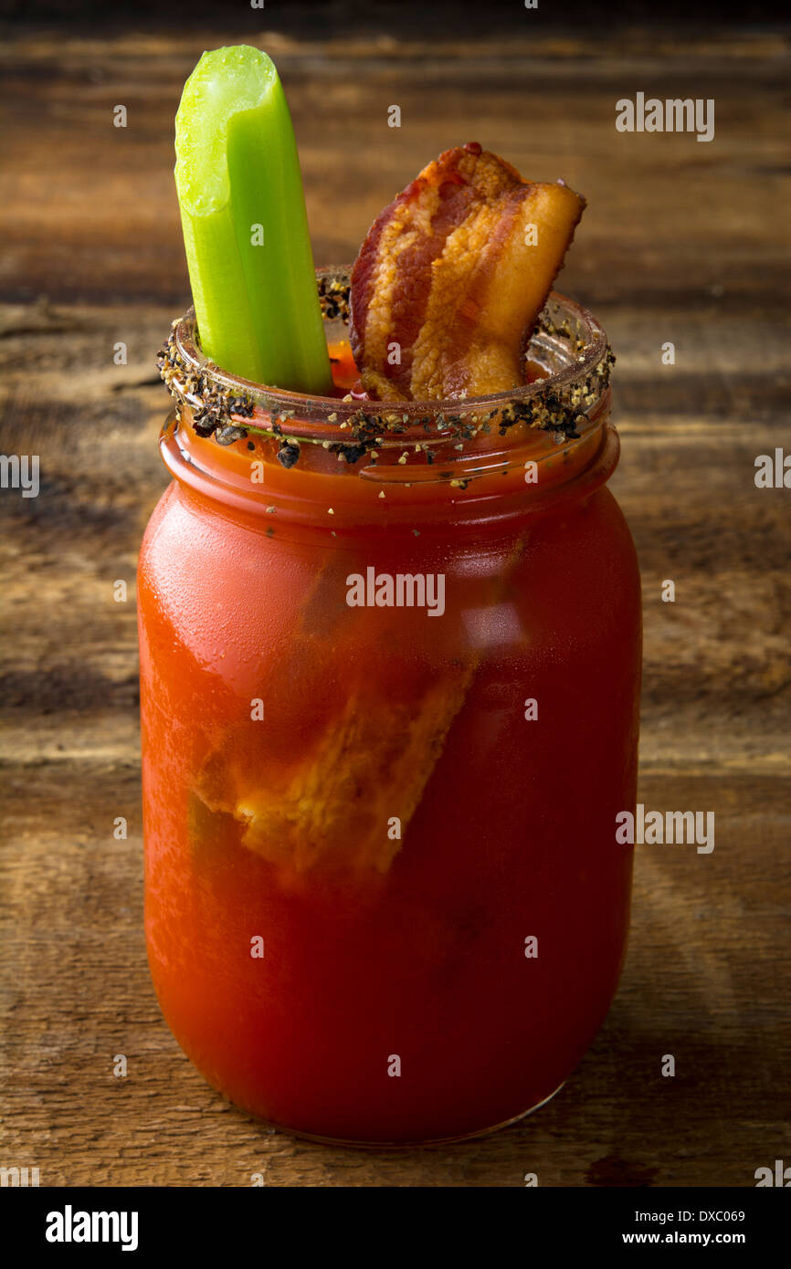 Mason jar Bloody Mary or Caesar with bacon on wood background Stock Photo