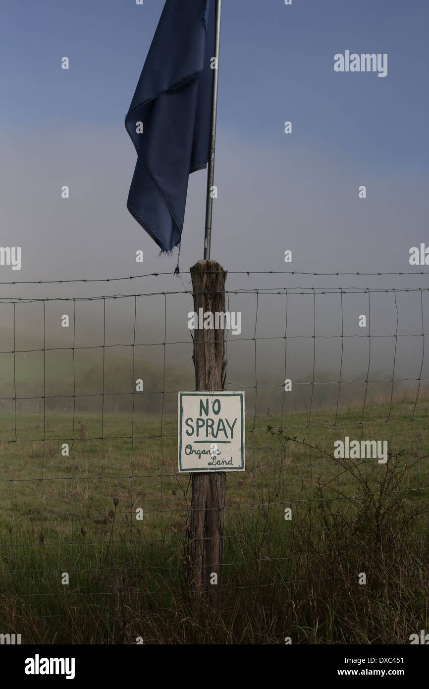 A sign on a fence near a northern California farm stating "no spray, organic land". Stock Photo